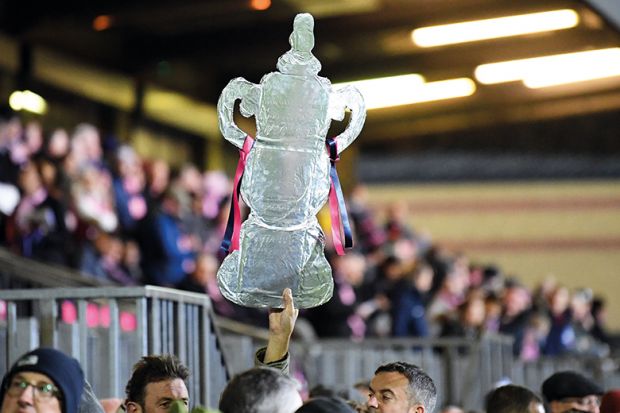 A foil replica FA Cup is held up high at Champion Hill in London to illustrate Degree apprenticeships: dont ruin something world is adopting